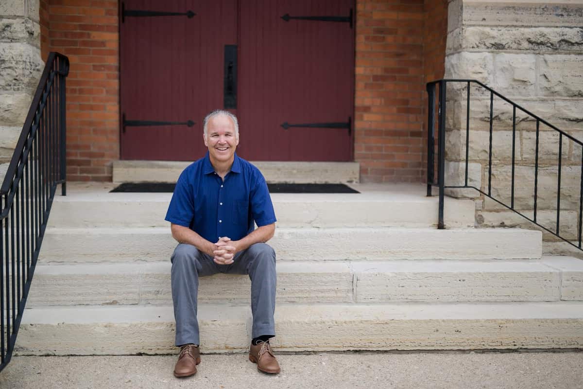 Chris Brauns seated on the front steps of a church