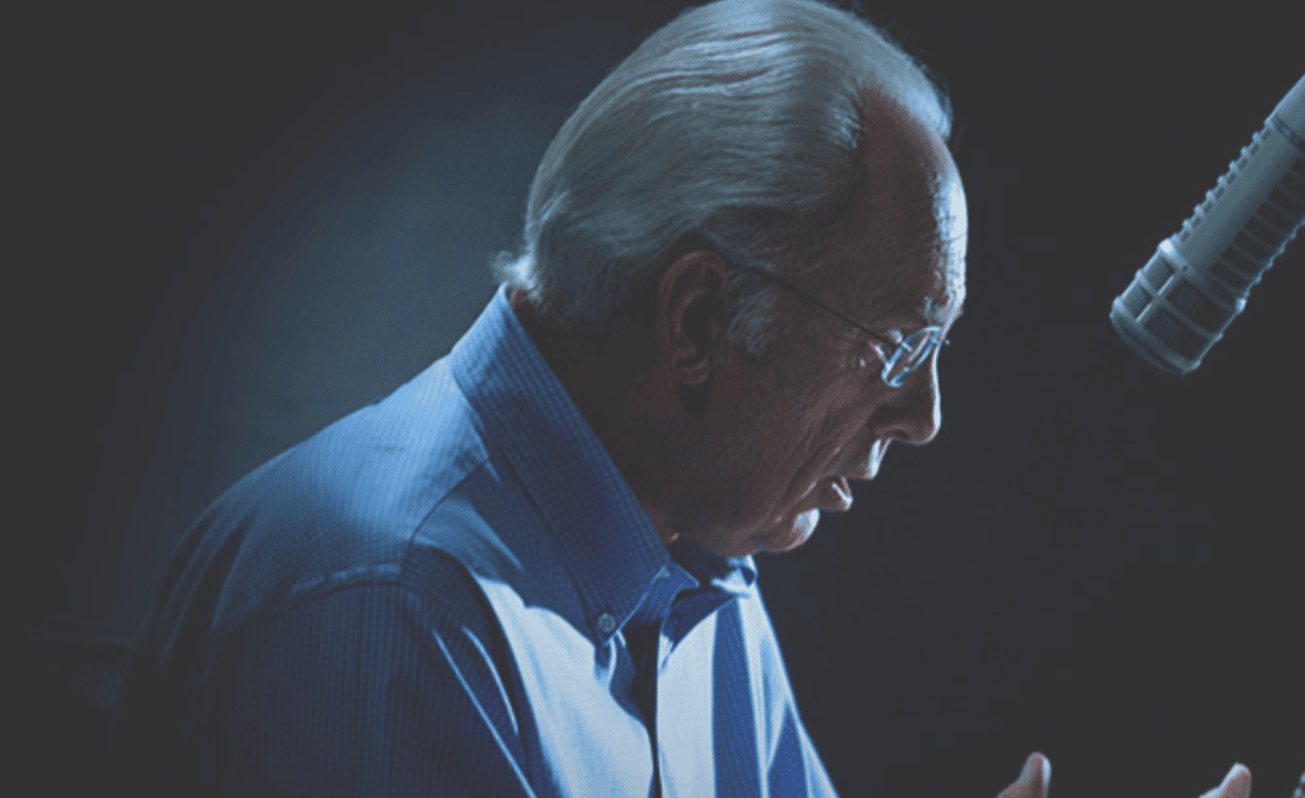 John MacArthur preaching at a microphone