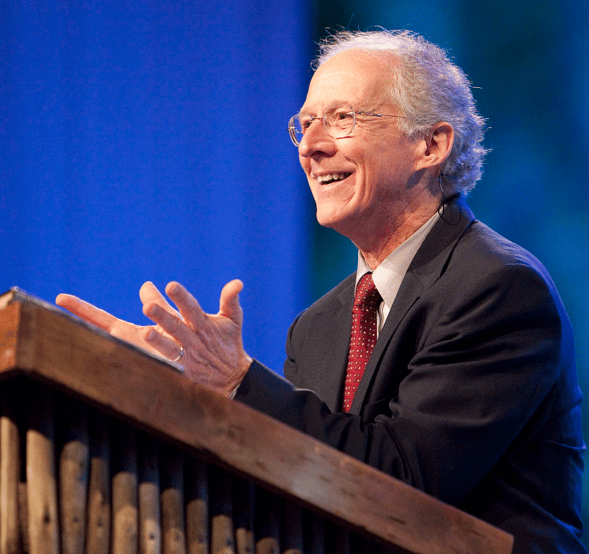 John Piper smiling as he preaches from a pulpit